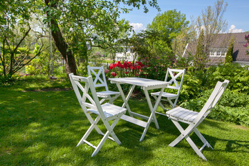 white wooden table and chairs standing on a lawn at the garden