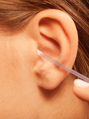 Wall Mural - Woman cleaning ear with cotton swabs closeup