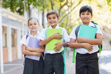 Wall Mural - Portrait of smiling school kids standing in campus