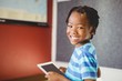© WavebreakmediaMicro - Portrait of schoolboy holding digital tablet in classroom