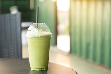 Green tea matcha smoothies in plastic cup. Interior coffee shop. Condensation on a cup (Selective focus and shallow depth of field)