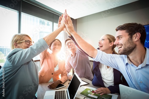 Business people giving high five at desk Poster Mural XXL