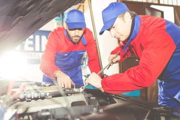 Two mechanics working on a car