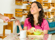 © Fotos 593 - Pretty brunette woman sitting by table inside bakery, receiving plate with chocolate bread and smiling
