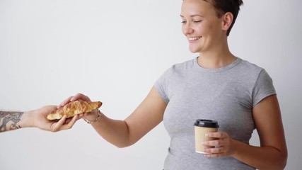 Wall Mural - Tattoed man hand gives tasty croissant to young woman that enjoys her coffee from paper cup take away