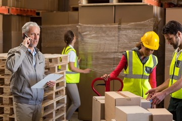 Focus of manager talking on the phone next to the workers 