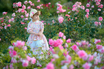 portrait of little girl outdoors in summer roses in the garden