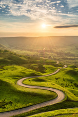 winding country road leading to edale in the english peak district with beautiful golden light shini