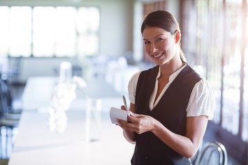 Wall Mural - Portrait of smiling waitress taking order