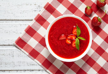 Natural organic fresh raw strawberry cream soup vegetarian cold sweet berry smoothie summer food on white wooden background table