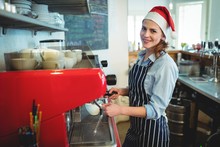 Portrait Of Happy Waitress Wearing Santa Hat At Cafe