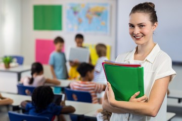female teacher with files standing in classroom