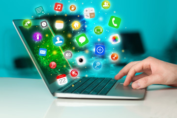 Hand pressing modern laptop with mobile app icons and symbols