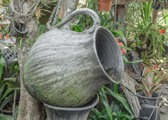 Old big earthen jar for water which has thallophytic plant cling, big water jar shaped like a glass in the garden