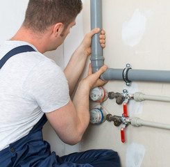 Wall Mural - Male plumber assembling water pipes.