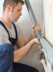 Wall Mural - Male plumber assembling water pipes.