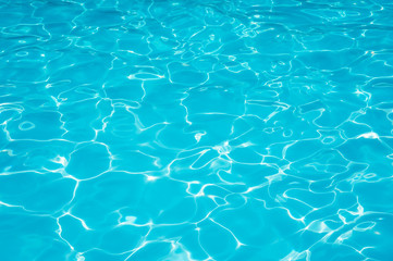 blue and bright water with sun reflection in swimming pool
