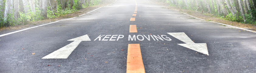 words of keep moving with white arrow and yellow line marking on road surface in the national park