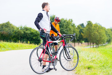 Zwei Sport Radfahrer, abgestiegen,  machen eine Pause