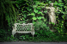 White Europe Style Bench Against Forest Back Ground With A Statu