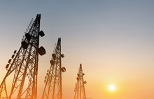 Silhouette, Telecommunication Towers With TV Antennas And Satellite Dish In Sunset