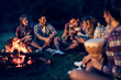 © NDABCREATIVITY - Friends enjoying music near campfire