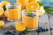 Orange and mango smoothie with granola and berries