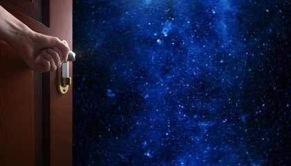 Wall Mural - hand opens empty room door to planet earth from the space. some