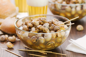 snails in blue bowl and glasses of beer on brown wooden background