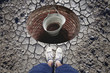 Top view of a man standing in front of built drinking water reservoir with empty metal rusty pail. Conceptual lack of drinking water.