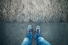 Point Of View Of A Man Standing On Asphalt Floor With Many Shoe Prints.