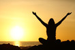 Happy woman raising arms looking at sunrise