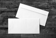 Photo of two blank envelopes on a dark wooden background. Back and front. Template for design portfolios. Mock-up for your design. Top view.