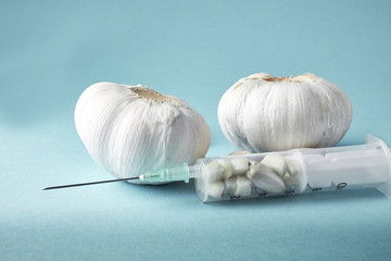 Injection with needle filled with garlic on green background. Concept image for garlic as natural antibiotic. Copy space