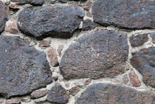 Wall Of The Medieval Fortress Of Large Stones. The Texture Is Very Old Stone Walls Of The Fortress. Background Of Cobblestones. The Ancient Construction Of Buildings From Natural Stones.