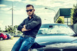© theartofphoto - Handsome bearded man on polished car in sunglasses