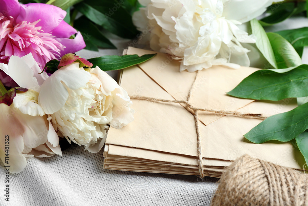 Composition with beautiful peony flowers and envelopes on white fabric closeup