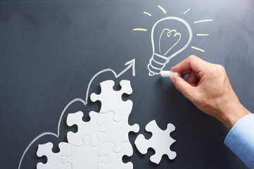 Aufkleber - Drawing light bulb on blackboard. Steps shaped jigsaw puzzle. Concept image of developing new idea.
