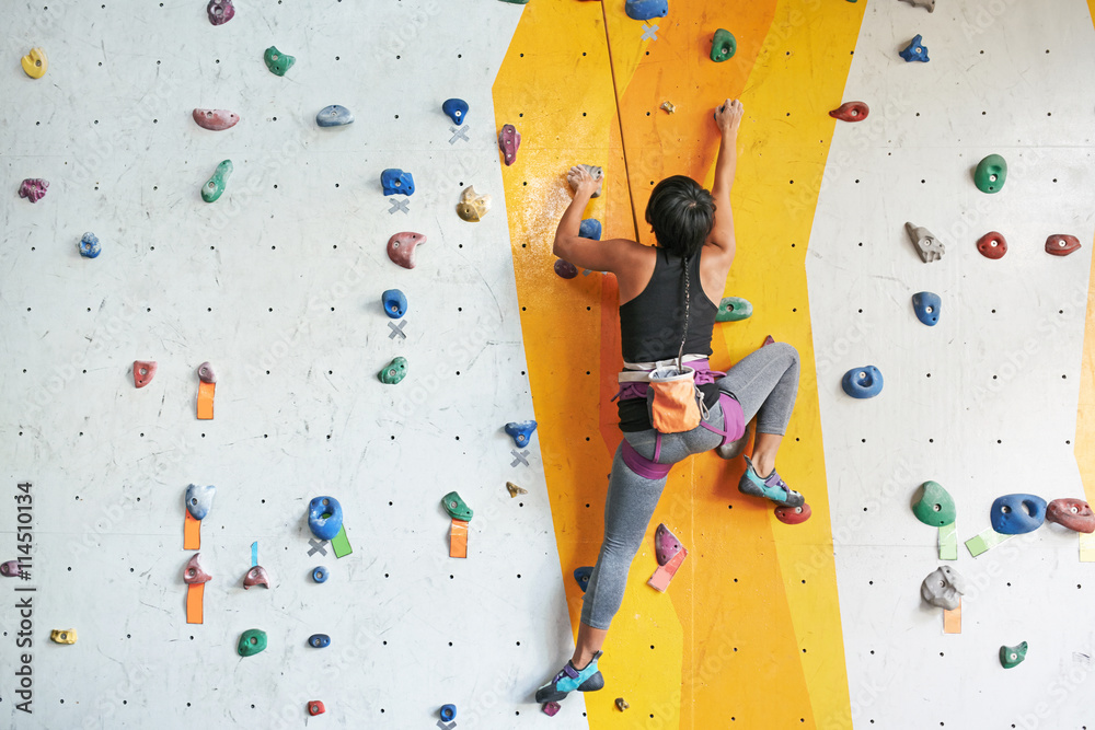 Back view of sportswoman climbing in the gym - obrazy, fototapety, plakaty 