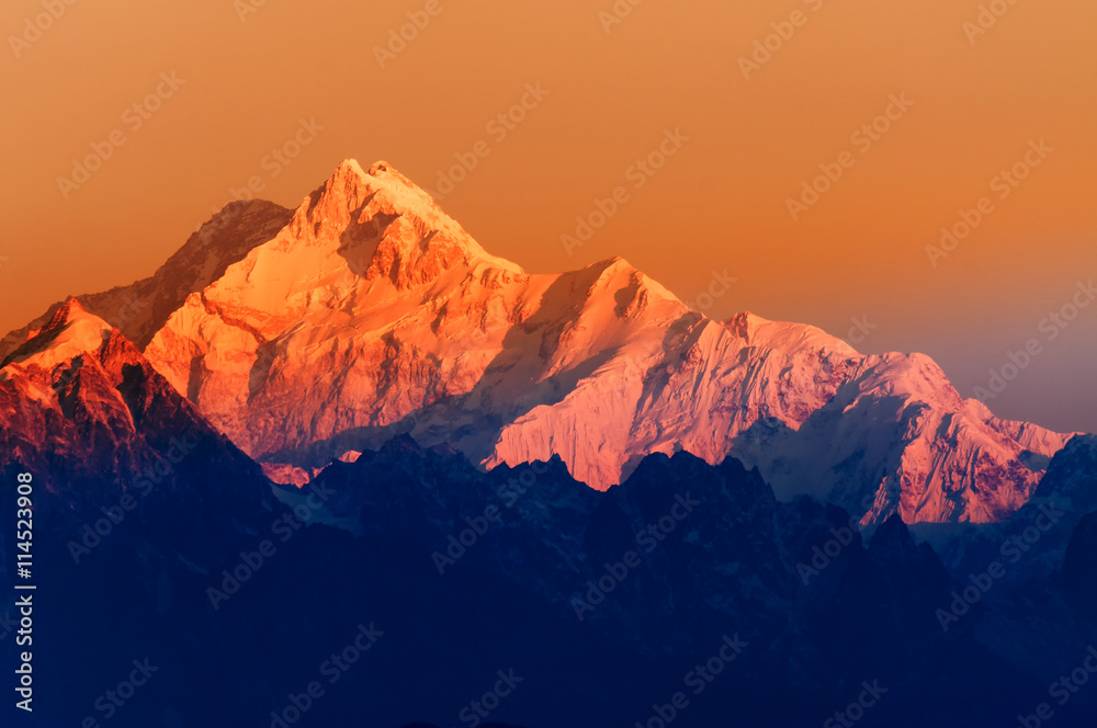 Beautiful first light from sunrise on Mount Kanchenjugha, Himalayan mountain range, Sikkim, India. Orange tint on the mountains at dawn. - obrazy, fototapety, plakaty 