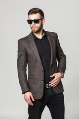 Studio portrait of handsome elegant young man in brown jacket po