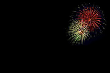 Green and red colorful holiday fireworks on black sky background.