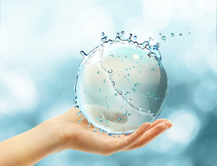 Wall Mural - Female hand holding abstract water ball splash on blur bokeh background
