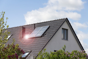 Wall Mural - house with solar panels on the roof with blue sky and lens flare