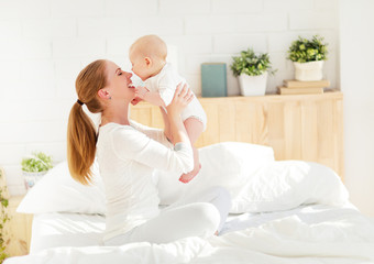 happy family mother with baby playing and hug in bed