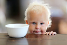 Cute Little One Year Old Baby Girl Next To Cereal Bowl In Kitche