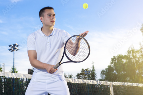 Jeune joueur de tennis lancer la balle en l'air, au service, mise au point s Poster