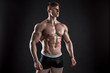 © nazarovsergey - Muscular bodybuilder guy doing posing over black background