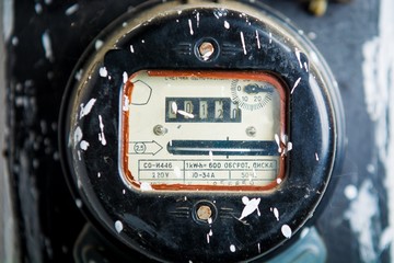 Old dusty electric meter on white wall