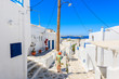 © pkazmierczak - A young woman tourist standing on Mykonos town street looking at sea, Cyclades islands, Greece